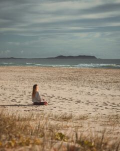 woman meditating on the beach
