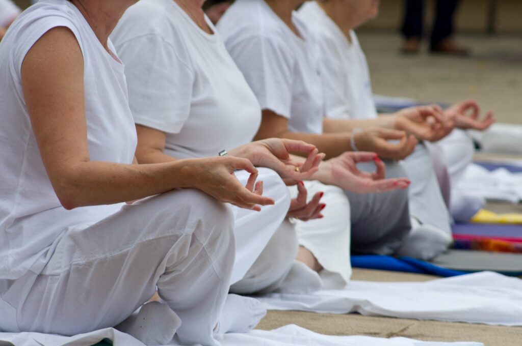 Group meditating in white with hands in mudra