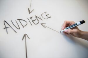 the word audience written on a white board with three arrows pointing to it and a hand with a pen
