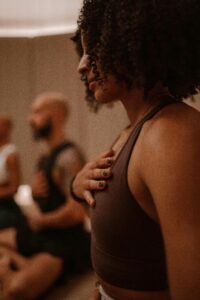 Woman meditating with black curly hair and hand on heart