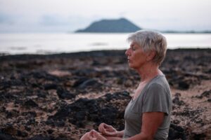 Older lady meditating on the beach