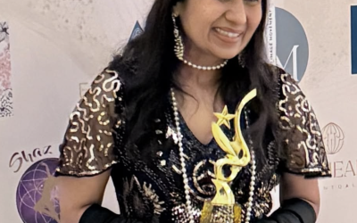 Deepika Jindal meditation teacher holding an award and wearing a black dress